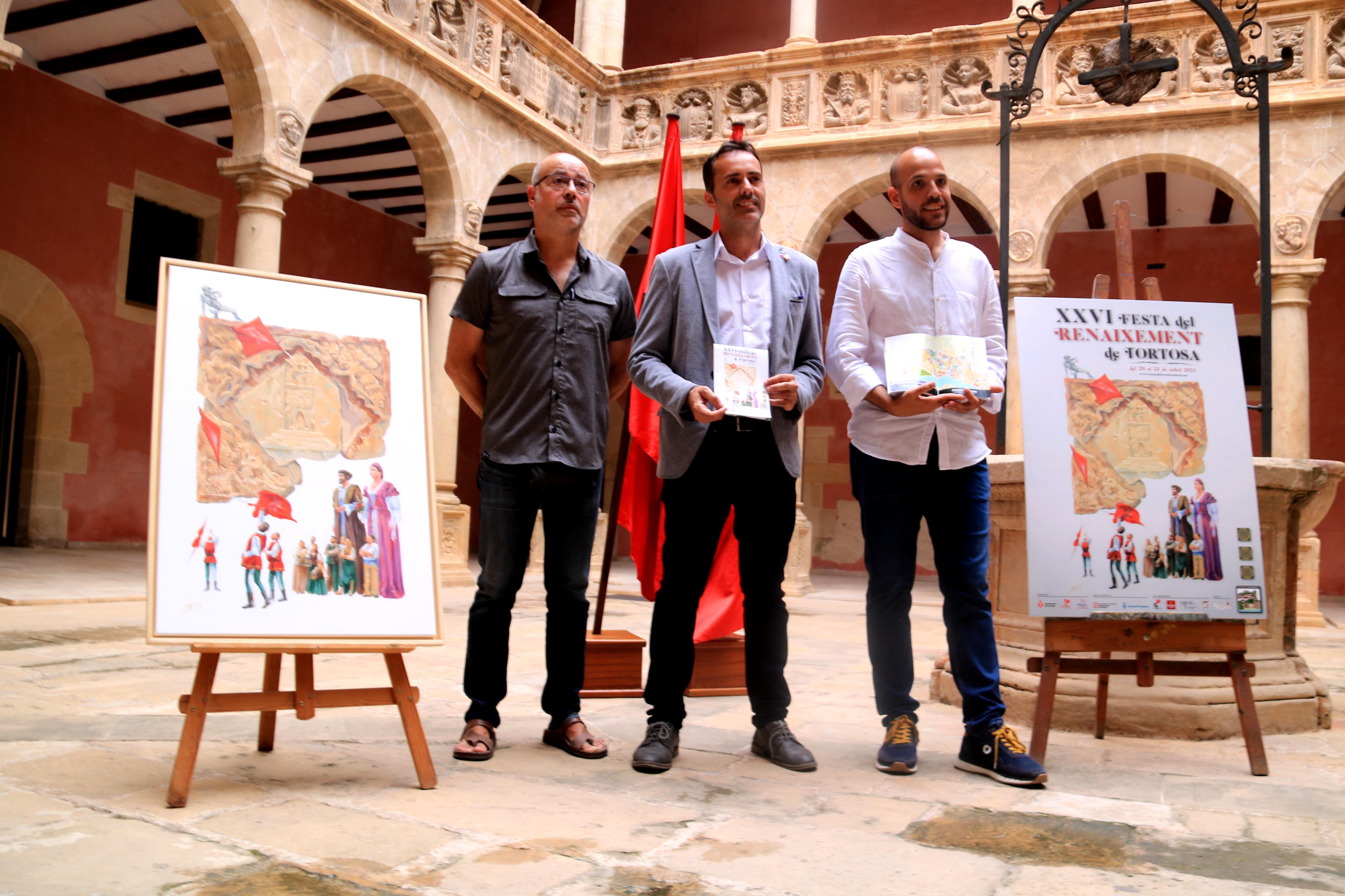 L'artista Àngel Algueró, l'alcalde de Tortosa, Jordi Jordan, i el regidor de la Festa del Renaixement, Víctor Grau, amb el programa i el cartell de la 26a edició del certamen