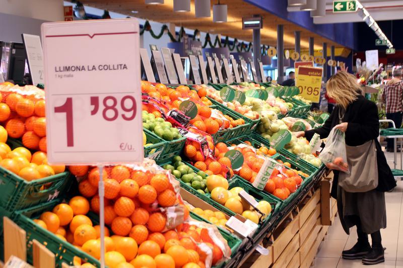 Una clienta compra pomes en una gran superfície en una secció on els productes han passat a estar gravats del 4% al 0%